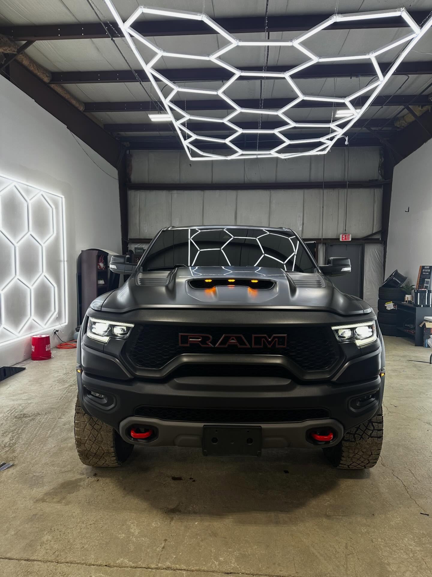 Matte black RAM 1500 TRX pickup under the hexagon LED light array at Prime Auto Lab